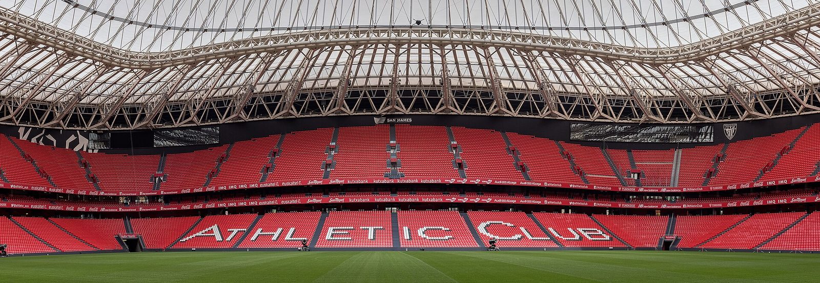 Interior del estadio San Mamés visto desde la tribuna, con el césped verde del campo en primer plano